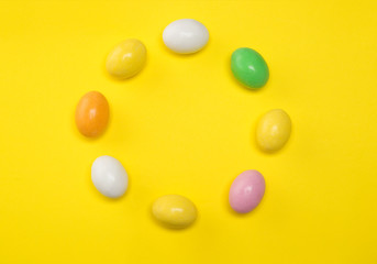 Colorful candy eggs on the yellow background.