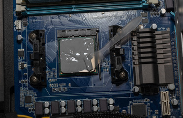 Applying thermal paste with spatula in CPU on motherboard. Close up