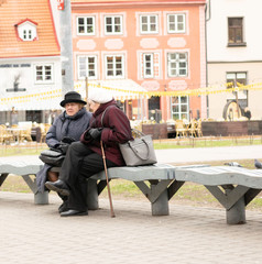 Two elderly ladies sitting on bench outdoors and talking.