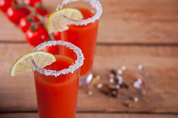 Bloody Mary Cocktail in glasses. Tomato Bloody Mary spicy drink on the wooden table.
