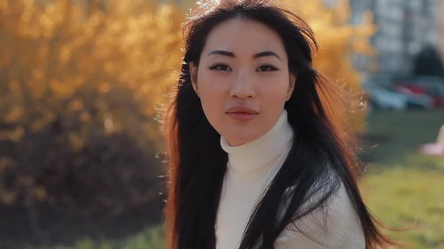 Asian woman turns face and looking at camera sitting outside on a nature