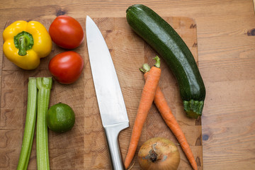 fresh vegetables on the cutting board and knife onion, tomatoes,carrot lemons., paprika, on wood background