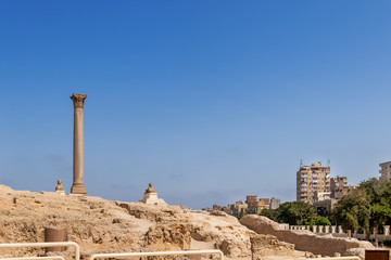 Fototapeta premium Pompey's Pillar, Roman triumphal column, with two Sphinx statues located at the Serapeum of Alexandria. Ancient architectural landmark in Egypt.
