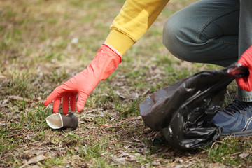 Hand of volunteer lift off litter ground. Spring cleaning in nature, outdoor trash and rubbish.