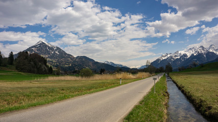 Fototapeta na wymiar Walgau im Frühling mit grünen Wiesen und Schnee auf den Bergeb