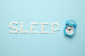 Sleeping pills and an alarm clock, insomnia concept. Night depression, anxiety.