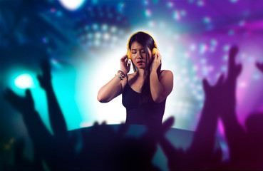 young attractive and happy Asian Chinese DJ woman remixing using deejay gear and headphones at...