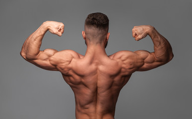 muscular super-high level handsome man posing on gray background