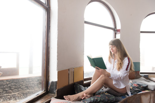 Woman reading book near window