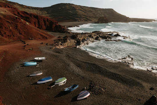 Modern boats located on rocky coast near waving sea and amazing hills on sunny day in wonderful countryside