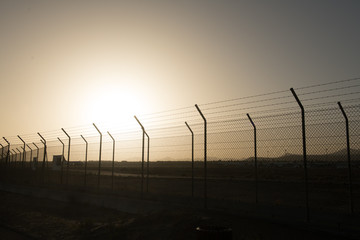 Bright sun behind security fence