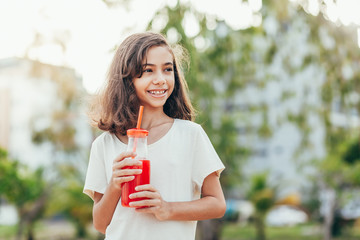 Portrait of young girl drinking juice in the park