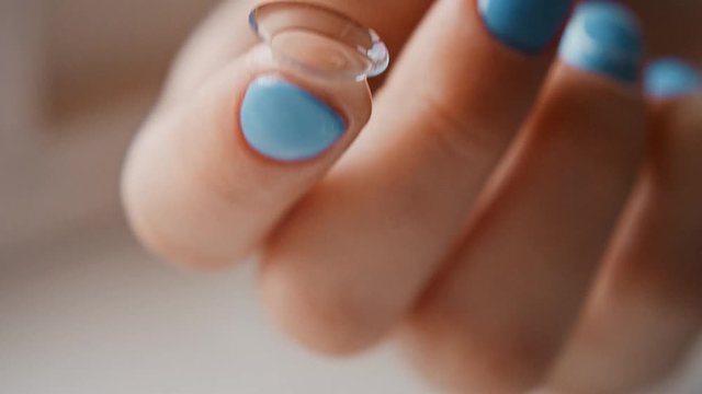 The girl takes out contact lenses from the container with the solution and touches their fingers, hands close-up. Women's fingers take lenses, crumple them and touch. Slow motion, 4K