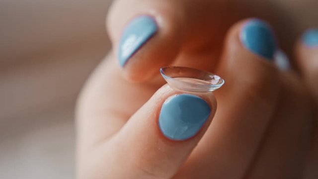 The girl takes out contact lenses from the container with the solution and touches their fingers, hands close-up. Women's fingers take lenses, crumple them and touch. Slow motion, 4K