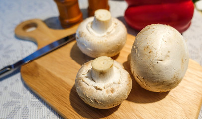 Fresh champignon mushrooms on a cutting board. Close-up. Vegetarian food.