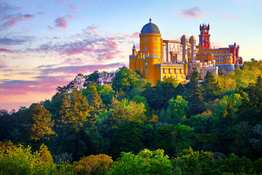 National Palace of Pena in Sintra, near Lisbon, Portugal. Picturesque landscape with dawn and green trees. Blue morning sky with clouds.