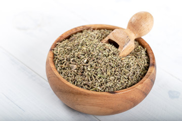 Dried fennel seeds in the wooden bowl on wooden background