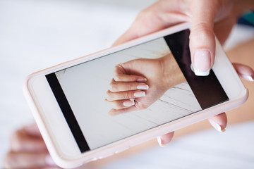 Woman making photo new manicure on camera her phone