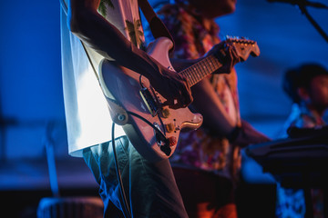 Naklejka premium Man playing guitar. Young hipster guitarist playing electric guitar on stage for background, soft and blur concept. Close up man's hand playing guitar. young musician playing guitar