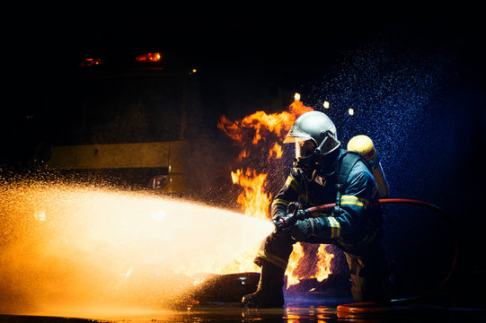 Unrecognizable male in firefighter uniform suppressing fire with heavy stream of water