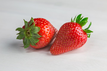 Two strawberries on white wood 