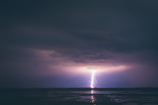 Amazing view of bright lightning shining on dark night sky over calm sea water in Thailand