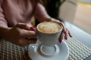 Female hand holding a white cup of coffee