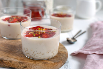 Healthy vegan dairy free dessert - tapioca pearls pudding with coconut milk and strawberry chia jam close up, served in glass jar