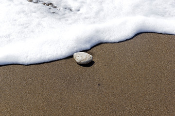 Fototapeta na wymiar A lonely stone on the sand in the surf.