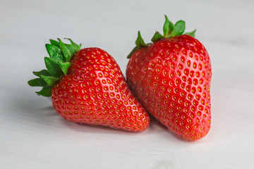 Two strawberries on white wood 