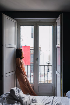 Young slim woman standing near big windows in the bedroom