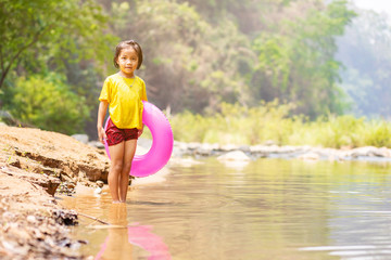 Little Asian girl running in water with her swim ring