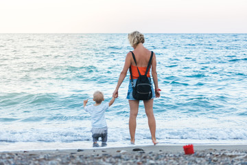 Fototapeta na wymiar Mother and son walking on sunset beach
