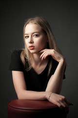 Portrait of the blonde young woman on black background.