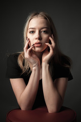 Portrait of the blonde girl on black background.