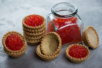 Tartlets filled with red caviar and a jar of red caviar, close-up, studio shot