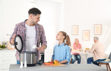 Father and daughter preparing food with modern multi cooker in kitchen