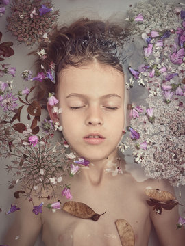 Girl lying in water among petals
