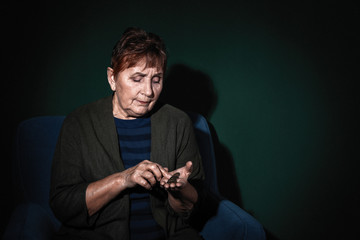 Poor senior woman with coins on color background. Space for text