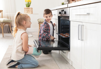 Little kids baking cookies in oven at home