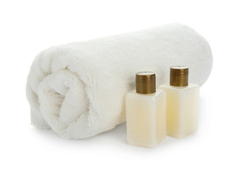 Fototapeta na wymiar Mini bottles with cosmetic products and towel on white background. Hotel amenities