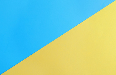 Blue and yellow paper sheets as colorful background, top view