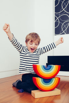 Blonde cute boy playing with waldorf rainbow puzzle