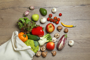 Fototapeta na wymiar Bag with fresh vegetables and fruits on wooden background, flat lay