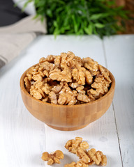 Walnut kernels in a wooden bowl on white background.