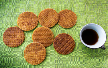 Stroopwafels with coffee on a table with green tablecloth