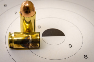 A 45 acp bullet with a paper target in the background