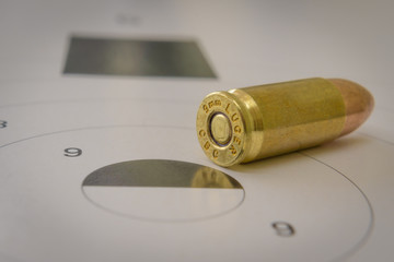 A 9mm bullet closeup with a paper target in the background