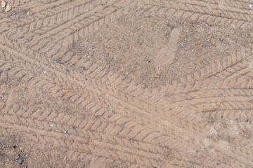 Car wheel on a dirt road on the brown dry soil ground texture background.