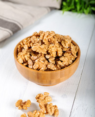 Walnut kernels in a wooden bowl on white background.